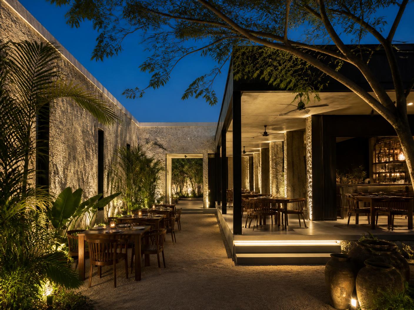 Restaurante contemporáneo iluminado entre jardines
